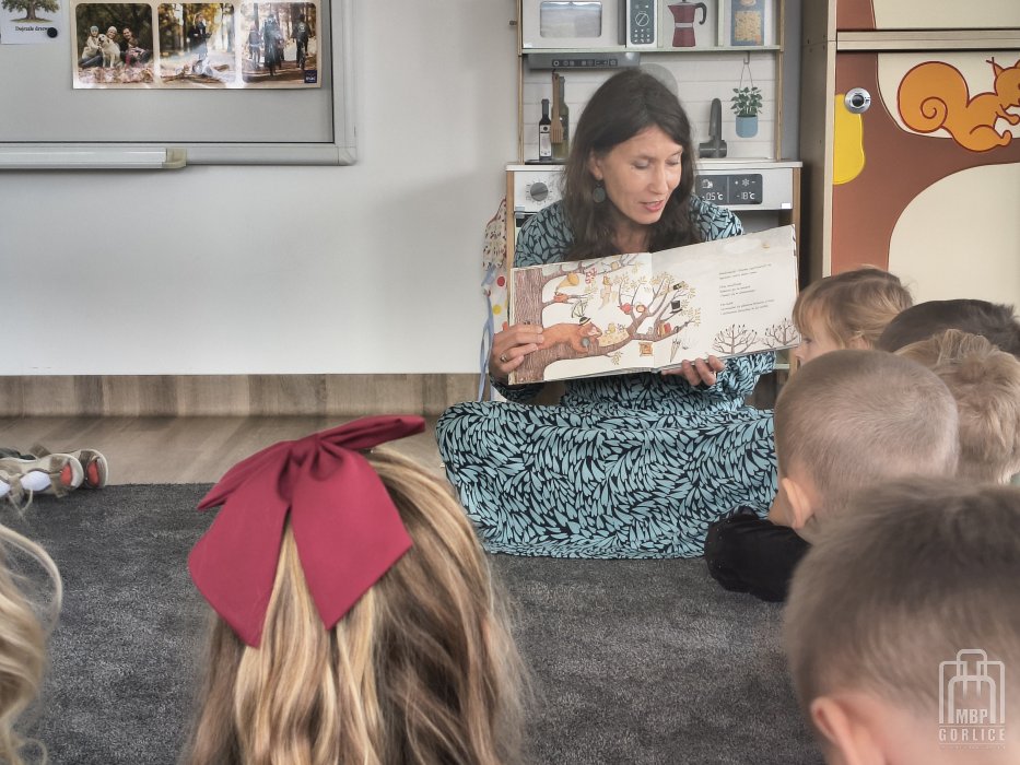 Biblioteka Gorlice, Cała Polska czyta dzieciom bibliotekarka prezentuje dzieciom ilustracje w książce